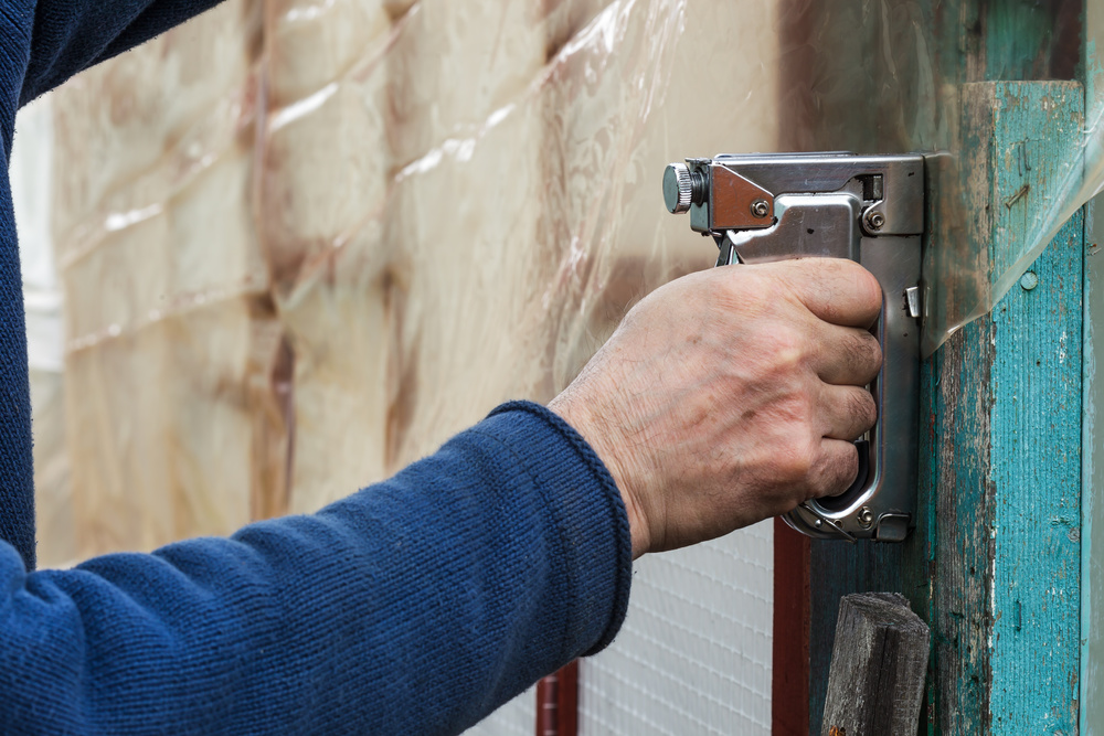 Staple gun fastened to insulation and upholstery material in a household and workshop repair setting