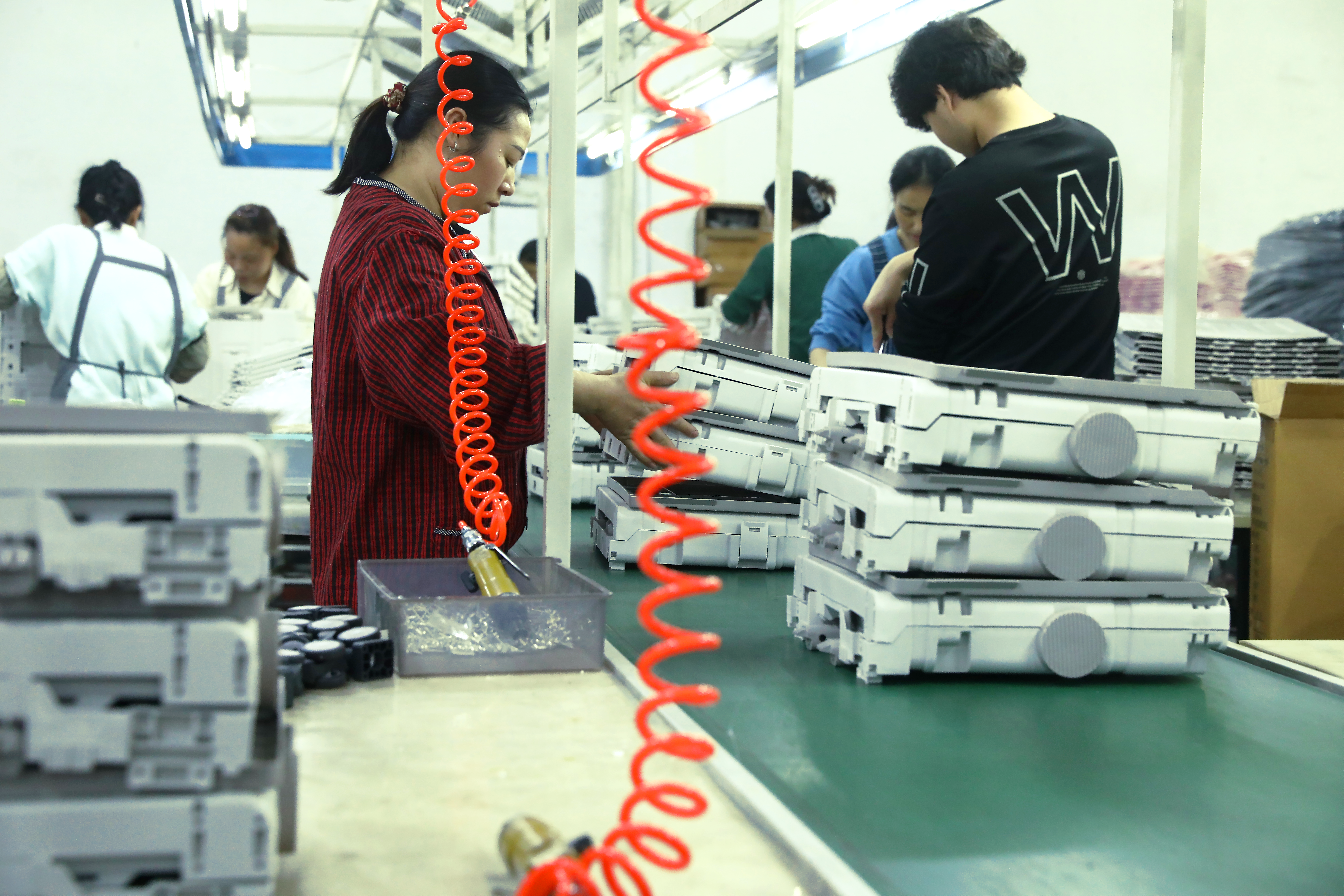 Standardized product assembly line at Xinhai Box, showing rows of foldable storage containers being assembled