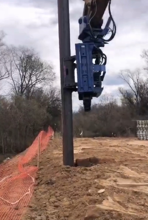 Side grip pile driver operating under low bridge