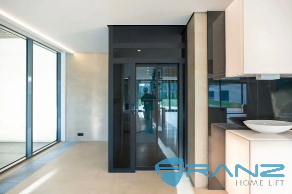 Four-sided panoramic glass home lift cabin installed in a private villa entrance hall