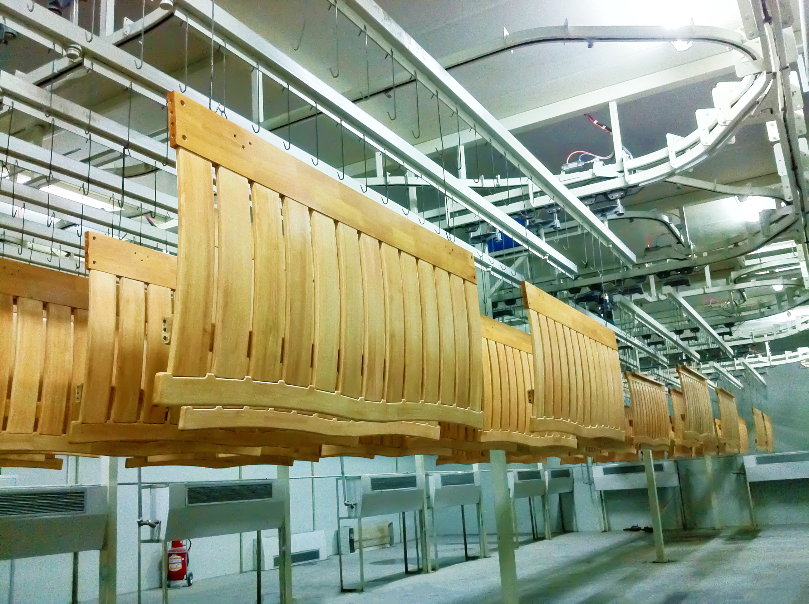 Wood furniture coating line in operation with automated conveyor and spray booth