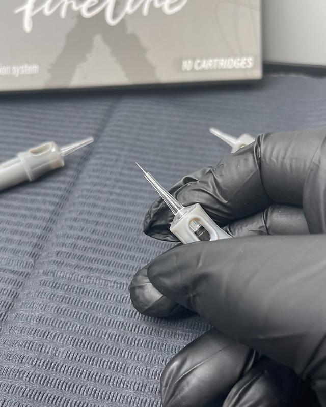 Tattoo artist using SPACEDRAGON cartridge needle in a professional studio
