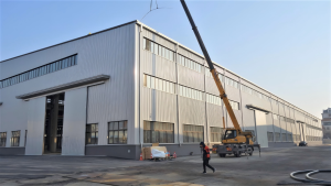 Outside the production plant, with lifting machinery for loading large irrigation equipment frames.