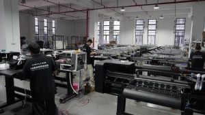 Xinflying technicians assemble DTF printer frames, wiring, and electrical systems at multiple production stations.