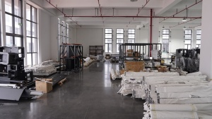 Metal profiles, machine frames, and boxed components for Xinflying DTF printers are organized in the factory storage area.