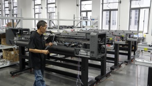 A technician installs and adjusts mechanical components inside a partially assembled Xinflying DTF printer.
