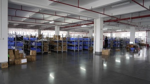 A clean Xinflying parts warehouse contains organized shelving, blue storage bins, and components for DTF printers.
