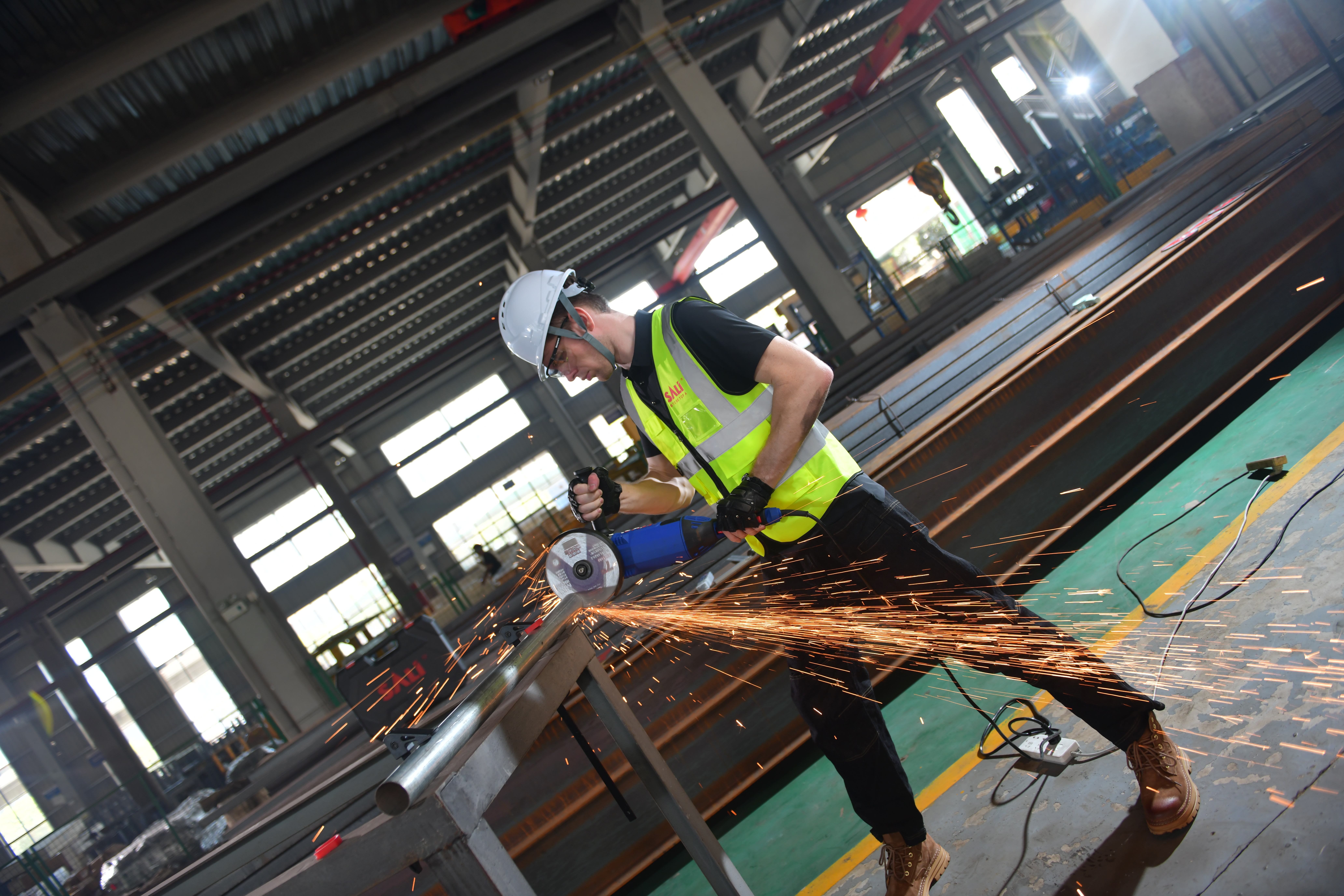 Angle grinder fitted with a cutting disc cutting metal in a fabrication workshop