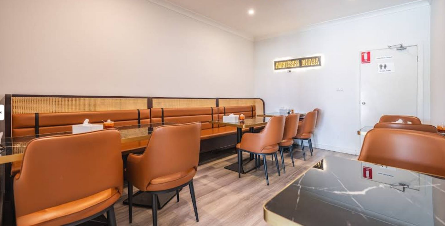 Restaurant dining area with wall-side booth bench seating and leather dining chairs in a completed commercial project
