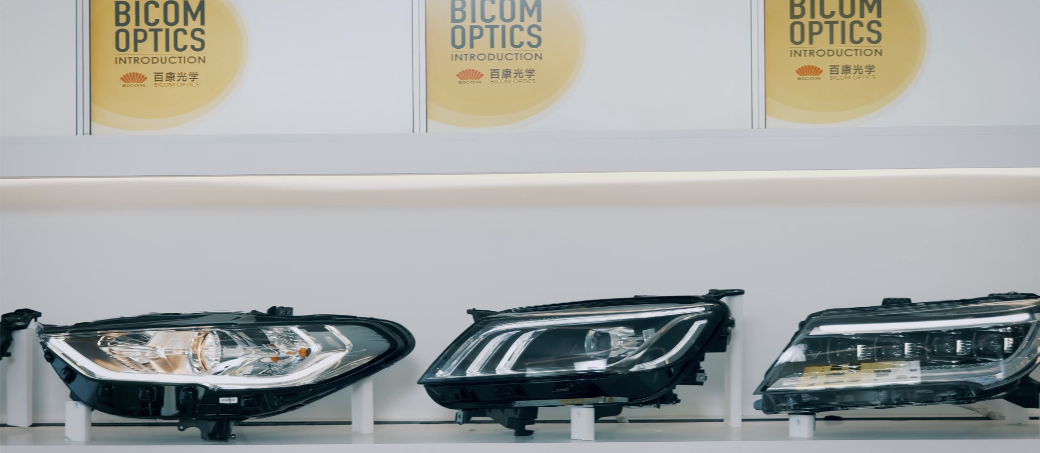 Automotive headlamp and lighting lens assemblies displayed as physical samples in an industry exhibition hall