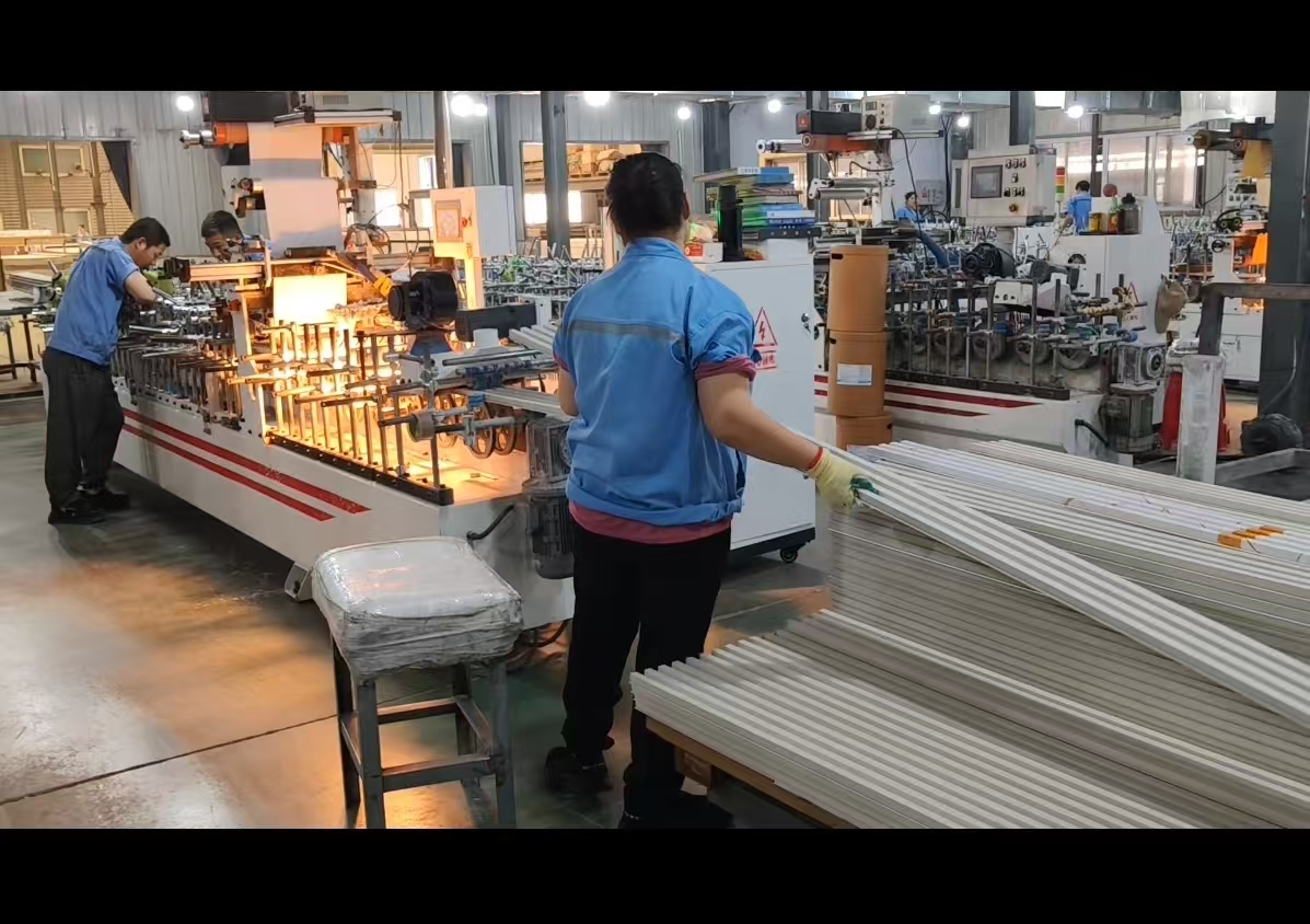 Workers operating an extrusion and lamination line producing composite wall profiles
