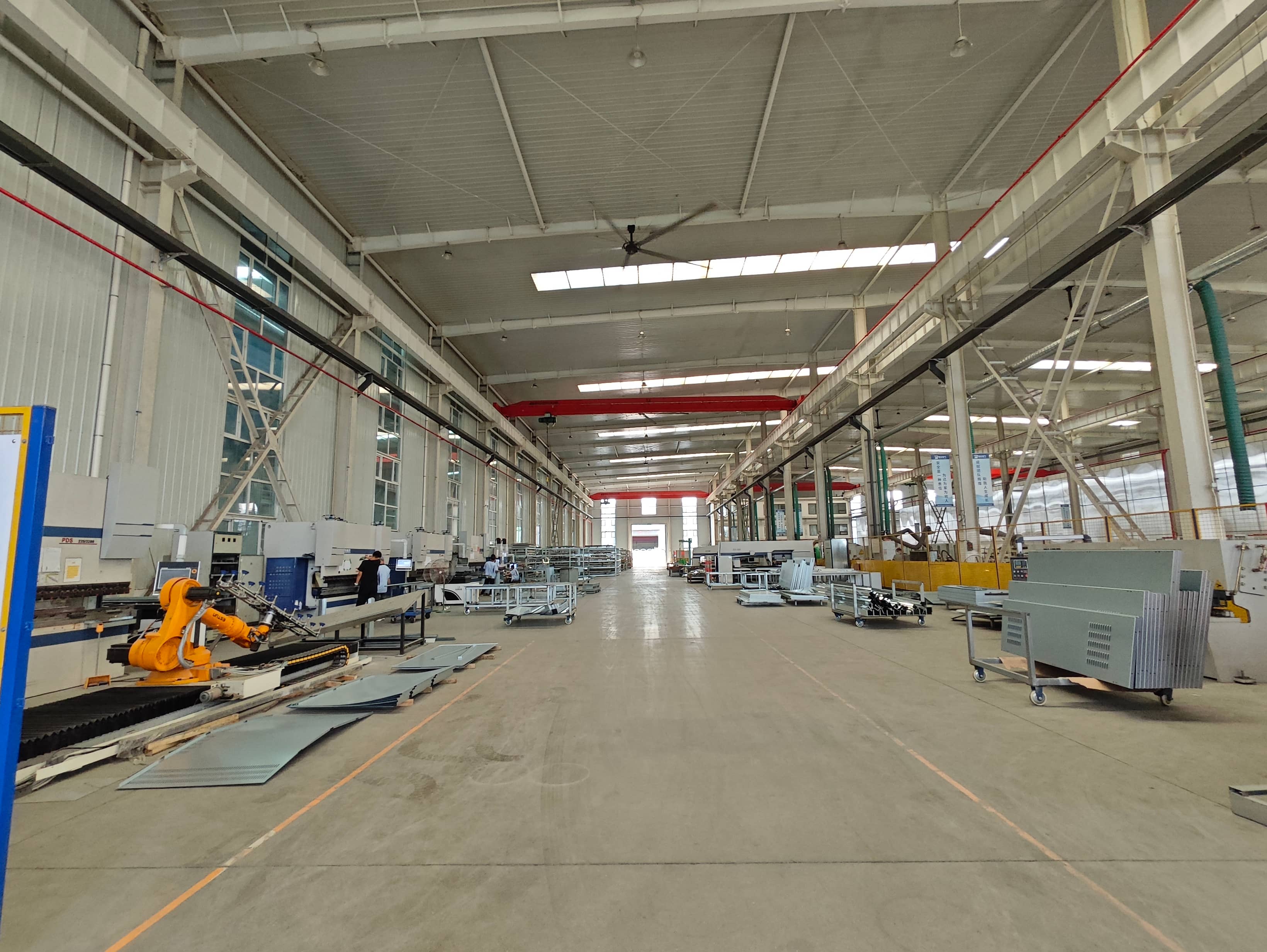 Prefabricated substation enclosure manufacturing workshop equipped with CNC sheet metal cutting and fabrication machinery. Steel plates are cut and processed into enclosure components for compact substations and electrical distribution equipment.