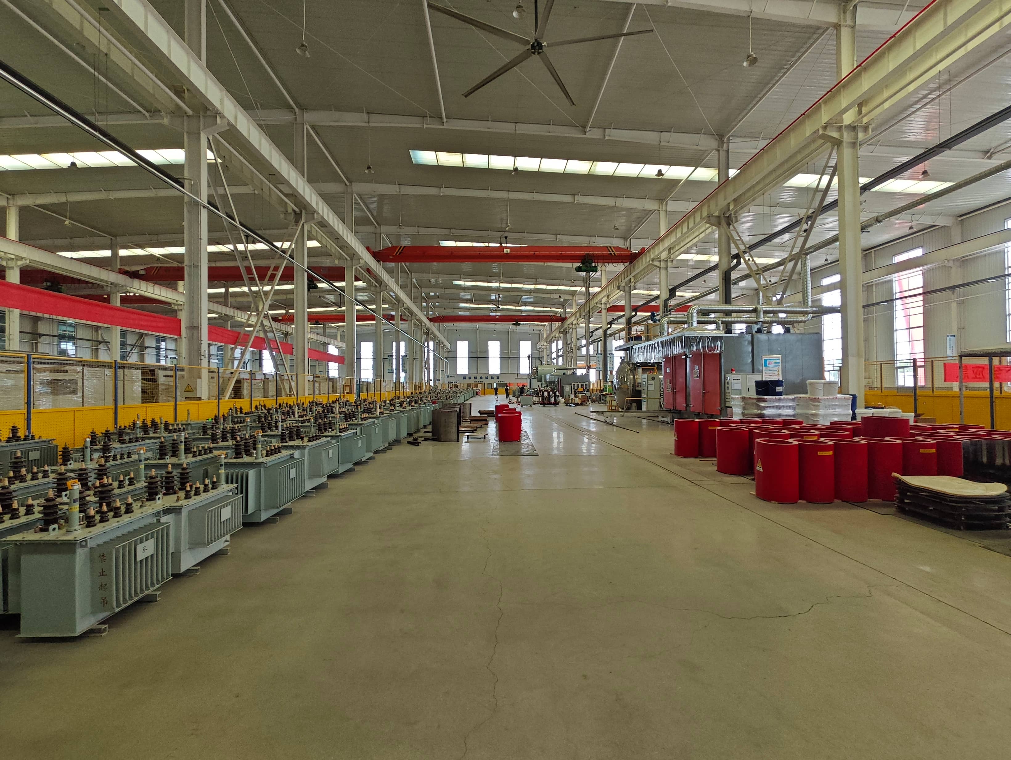 Transformer production workshop for power and distribution transformers, with areas for iron core assembly, vacuum drying, and insulating oil filling. These processes are part of the manufacturing and insulation treatment of oil-immersed transformers.